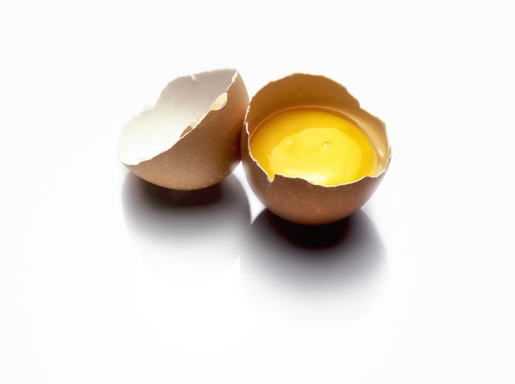 close up one broken raw egg isolated on white background with shadow effect